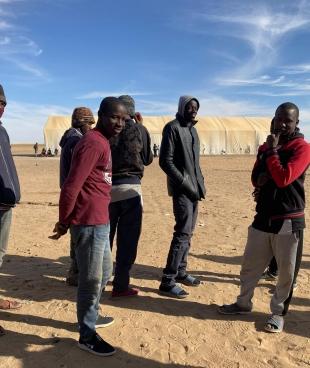Un groupe de jeunes hommes attendant pour recevoir de la nourriture à Assamaka, après avoir été expulsés d'Algérie. Niger. Mars 2021.