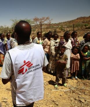 Un employé MSF auprès des femmes qui attendent avec leurs enfants une consultation médicale dans une clinique mobile du village d'Adiftaw, dans la région nord éthiopienne du Tigré.