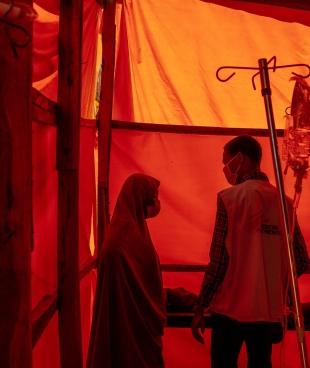 Un infirmier MSF, dans la zone de triage du CTC de MSF à Kano, s'occupe de Hafsat Auwal, aux côtés de sa mère, une patiente de 10 ans atteinte du choléra. Hafsat et sa famille vivent à Kano depuis longtemps.