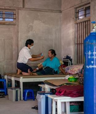 Un membre des équipes MSF au chevet d'une patiente touchée par la Covid-19, dans la clinique MSF de l'État de Kachin. Octobre 2021. Myanmar.