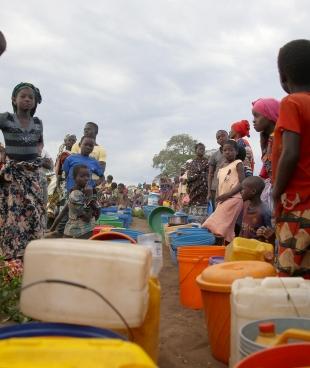 Des dizaines de personnes déplacées patientent après l'approvisionnement de 8 000 litres d'eau par camion dans un espace ouvert à la périphérie de Mueda,