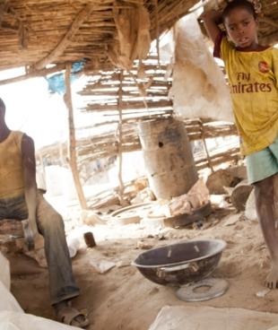 Des enfants travaillent dans un site d’extraction d’or à Bagega. Ibrahim (à droite) 10 ans doit alimenter la broyeuse avec les pierres concassées.