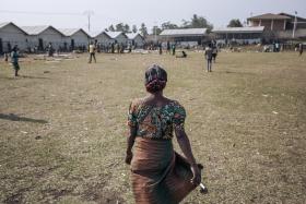 Agrippine, veuve déplacée de 53 ans, marche au sein du site informel de déplacés du stade de Rugabo, dans le centre de Rutshuru.