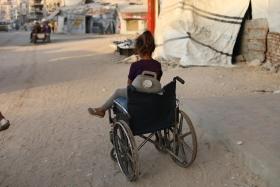 Une enfant près d'un fauteuil roulant qu'elle utilise pour transporter des jerricans d'eau, dans la ville de Gaza, en raison de la destruction systématique des infrastructures hydrauliques par Israël.