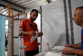 Un membre du personnel de MSF consulte le dossier médical de Saad Hussein, contraint de vivre avec un fixateur externe depuis qu'il a été blessé en 2025 lors d'une distribution alimentaire organisée par la Fondation humanitaire de Gaza. 