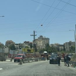 Des personnes attendent devant une barrière israélienne qui bloque l'accès à une route principale menant à Hébron. Beaucoup vont finir par passer à pied, malgré les risques. Ceux qui ont besoin de soins médicaux ou qui ne peuvent pas marcher sont restés bloqués, dans l'impossibilité de traverser. Cisjordanie, 14 juin 2025
