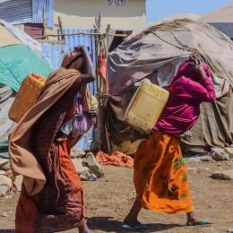 Des femmes transportent des bidons alors qu'elles reviennent du point de distribution d'eau du camp de personnes déplacées de Banban, à Baidoa, en Somalie.