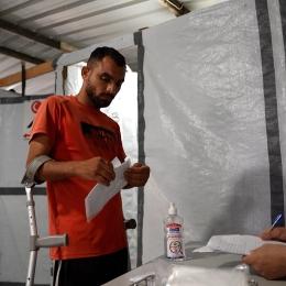 Un membre du personnel de MSF consulte le dossier médical de Saad Hussein, contraint de vivre avec un fixateur externe depuis qu'il a été blessé en 2025 lors d'une distribution alimentaire organisée par la Fondation humanitaire de Gaza. 