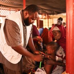 Un membre du personnel de MSF mesure la circonférence du bras à mi-hauteur de Maniru, âgé de 2 ans, au centre de nutrition thérapeutique ambulatoire situé dans l'État de Kebbi, au nord-ouest du Nigeria.