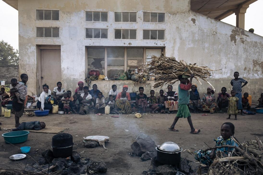 A displaced child carries maize stalks on his head to make a fire for cooking, near the stands of Rugabo Stadium, which has been turned into a site for displaced people, in central Rutshuru.